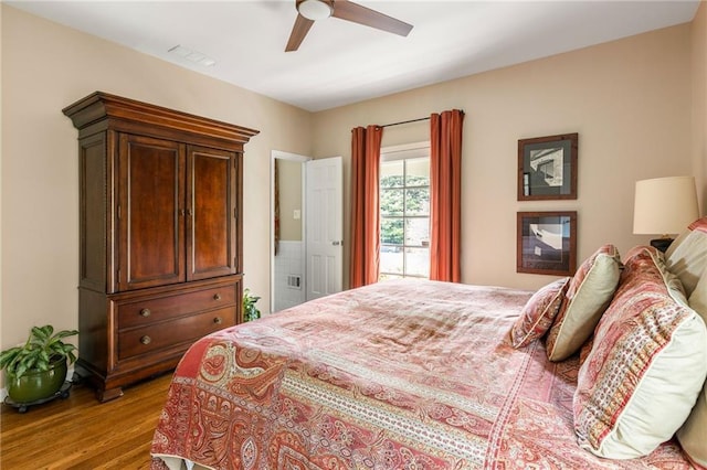 bedroom featuring ceiling fan, visible vents, and wood finished floors