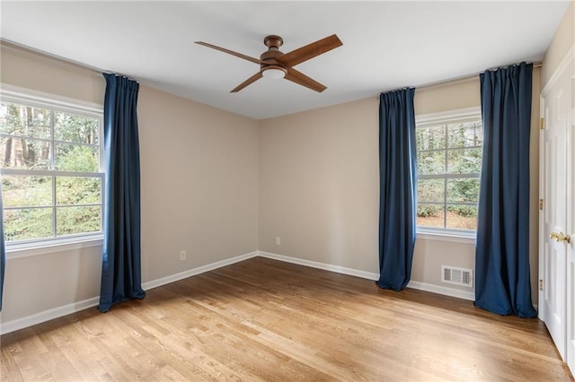 empty room featuring light wood-type flooring, baseboards, visible vents, and ceiling fan