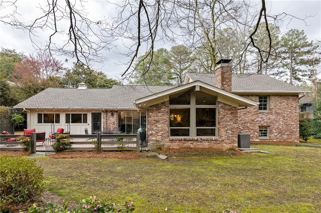 back of house featuring brick siding, a yard, and a chimney