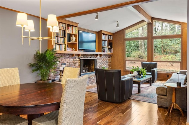 living area with vaulted ceiling with beams, a brick fireplace, and wood finished floors