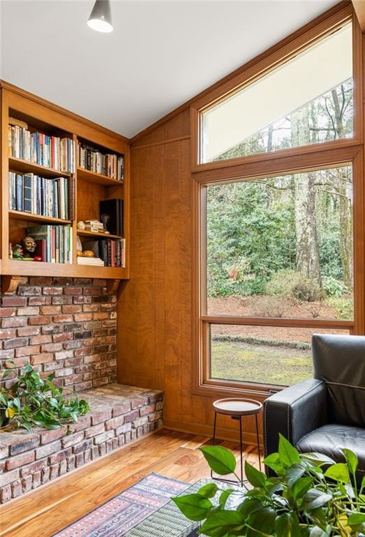 sitting room featuring wood walls, vaulted ceiling, and wood finished floors