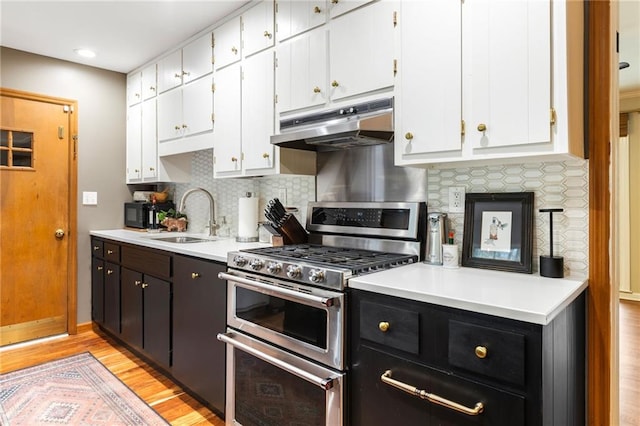 kitchen with range with two ovens, a sink, white cabinetry, and under cabinet range hood