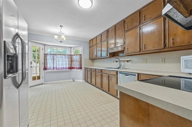 kitchen with appliances with stainless steel finishes, pendant lighting, range hood, sink, and crown molding