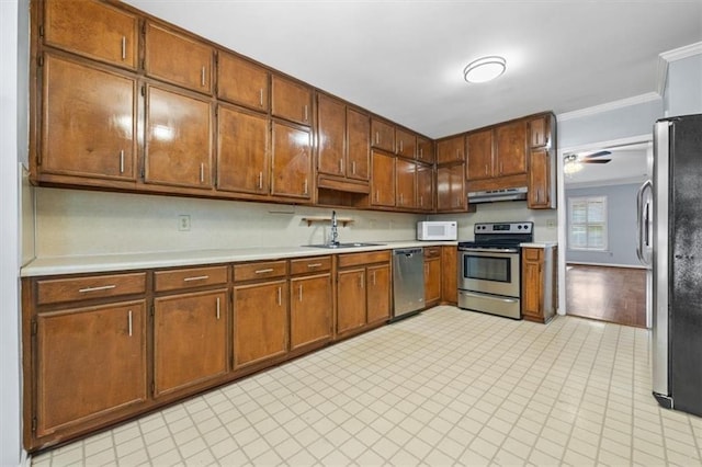 kitchen with crown molding, appliances with stainless steel finishes, sink, and ceiling fan