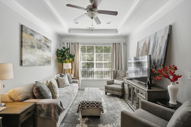 living room with ornamental molding, a tray ceiling, and ceiling fan