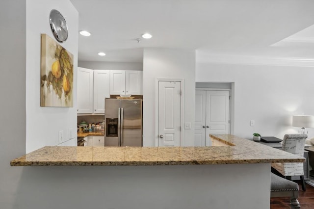 kitchen with light stone countertops, kitchen peninsula, white cabinetry, dark wood-type flooring, and stainless steel fridge with ice dispenser