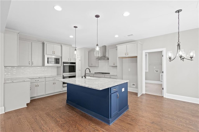 kitchen with stainless steel appliances, wall chimney range hood, dark wood-type flooring, and white cabinets