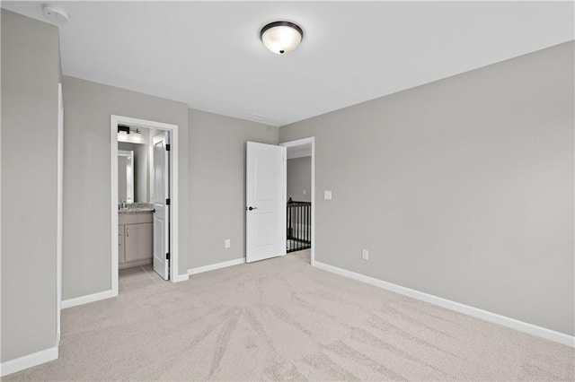 unfurnished bedroom featuring baseboards, connected bathroom, and light colored carpet