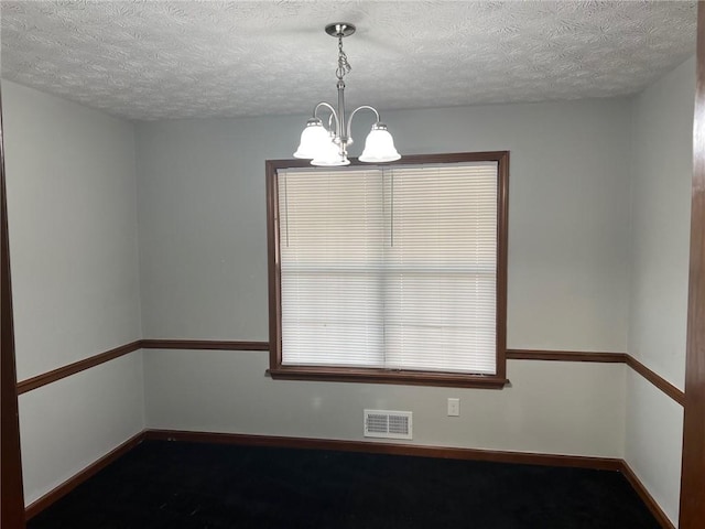 spare room featuring visible vents, a textured ceiling, baseboards, and an inviting chandelier