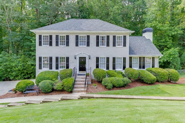 2903 Brookshire Way, Duluth, GA 30096 - colonial home featuring a chimney, a front yard, stucco siding, and roof with shingles