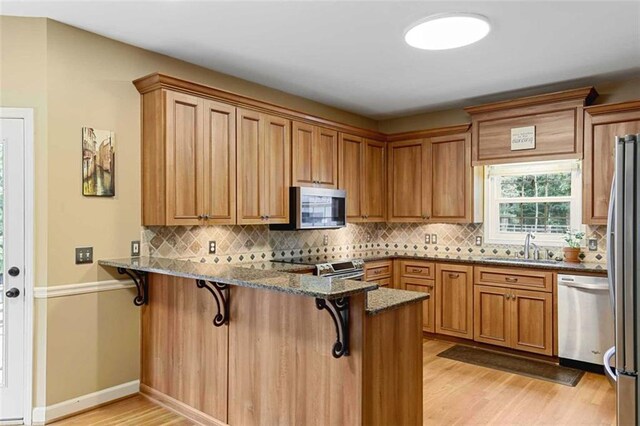 2203 Arbor Hill Rd, Canton, GA 30115 - kitchen with stainless steel appliances, light wood finished floors, a peninsula, a sink, and dark stone counters