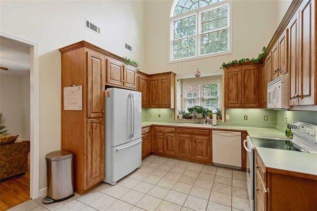 2203 Arbor Hill Rd, Canton, GA 30115 - kitchen with white appliances, a towering ceiling, a sink, brown cabinetry, and light countertops
