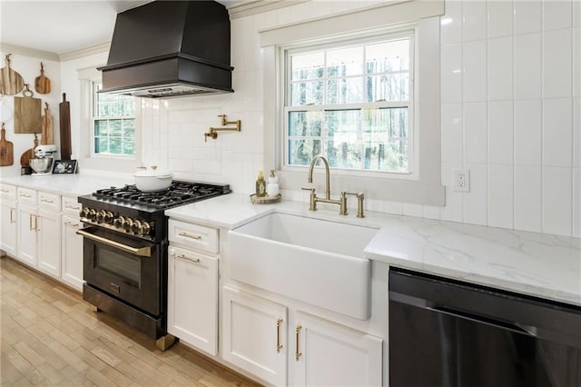 kitchen featuring light stone counters, premium range hood, a sink, dishwasher, and gas range