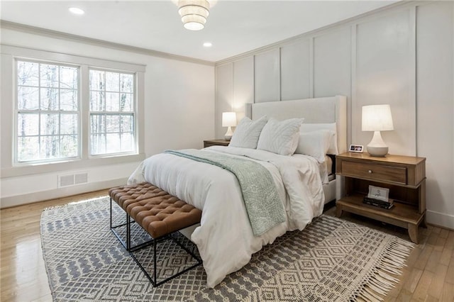 bedroom with recessed lighting, visible vents, baseboards, light wood-style floors, and ornamental molding