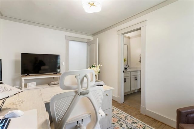 office space featuring crown molding, baseboards, a sink, and light wood finished floors