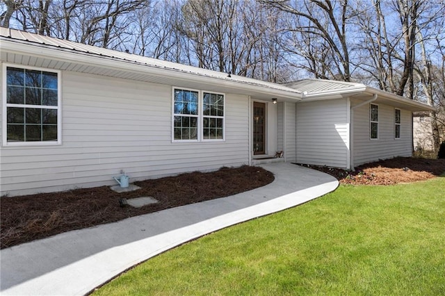 doorway to property featuring metal roof and a lawn