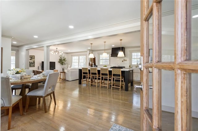 dining space with ornamental molding, light wood-type flooring, and a healthy amount of sunlight