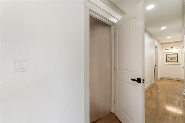 hallway featuring light wood finished floors, baseboards, and recessed lighting