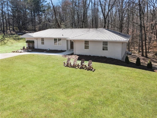 ranch-style house with metal roof, concrete driveway, a standing seam roof, and a front yard