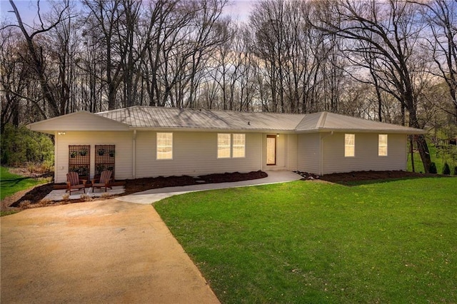 ranch-style home with a patio area, metal roof, and a front lawn