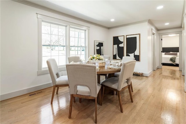 dining area with ornamental molding, visible vents, light wood-style floors, and baseboards