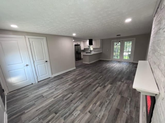 unfurnished living room with dark wood finished floors, recessed lighting, a textured ceiling, and baseboards