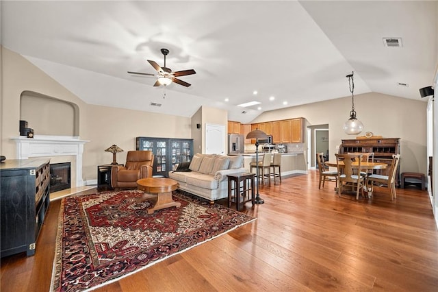 living room featuring lofted ceiling, light hardwood / wood-style flooring, and ceiling fan