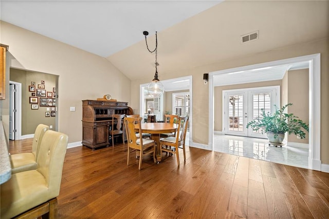 dining area featuring hardwood / wood-style flooring, lofted ceiling, and french doors