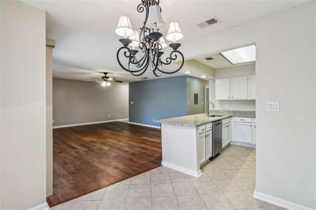 kitchen featuring a peninsula, a sink, white cabinets, light stone countertops, and pendant lighting