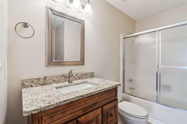 bathroom with enclosed tub / shower combo, vanity, and toilet