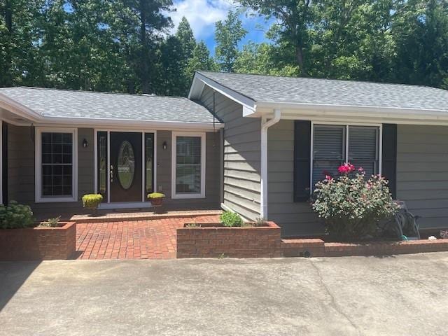 doorway to property with a shingled roof