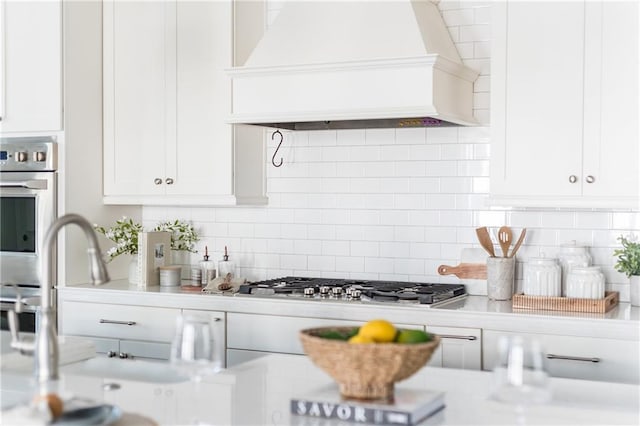 kitchen featuring tasteful backsplash, stainless steel gas stovetop, white cabinets, and custom exhaust hood