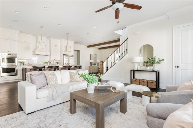 living room featuring ceiling fan, crown molding, beamed ceiling, and light hardwood / wood-style floors