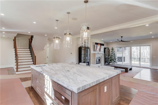 kitchen with stainless steel microwave, hanging light fixtures, sink, and a large island with sink