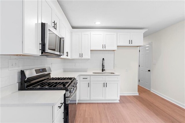 kitchen featuring white cabinets, sink, light hardwood / wood-style flooring, appliances with stainless steel finishes, and tasteful backsplash