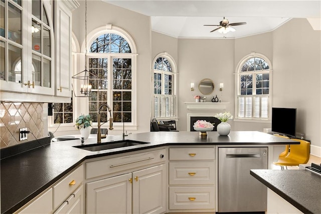 kitchen with dishwasher, dark countertops, open floor plan, a sink, and backsplash