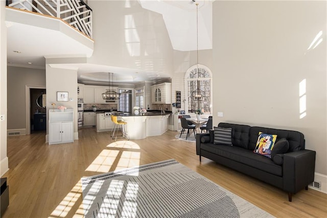 living room with ornamental molding, light wood-type flooring, and an inviting chandelier