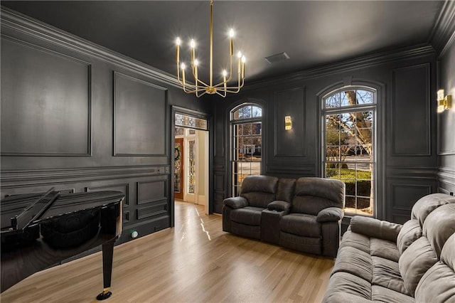 interior space featuring ornamental molding, light wood-style floors, a chandelier, and a decorative wall