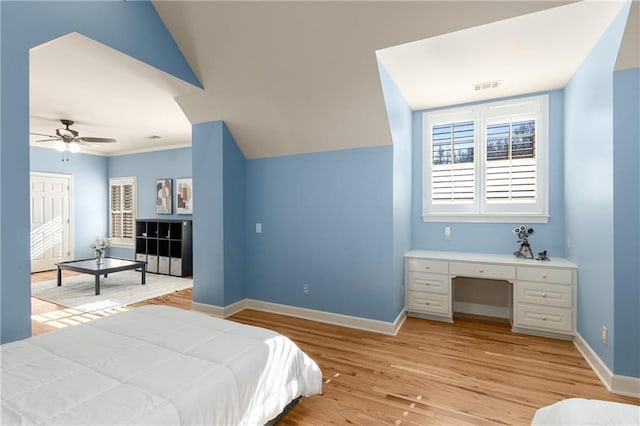 bedroom featuring ceiling fan, visible vents, baseboards, light wood-style floors, and built in desk