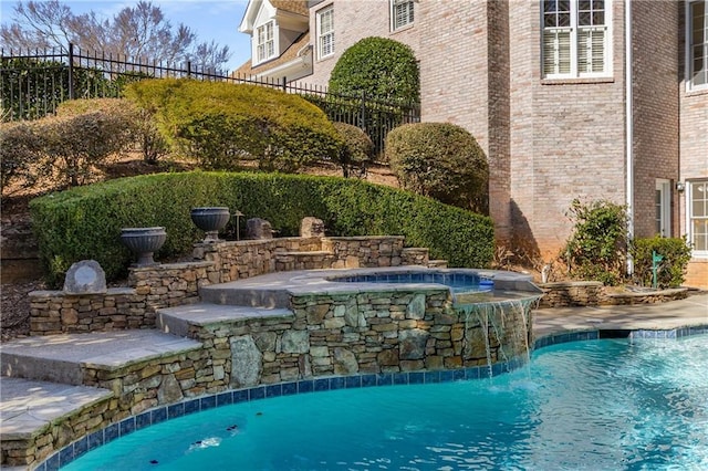 view of swimming pool featuring fence, a fenced in pool, and an in ground hot tub