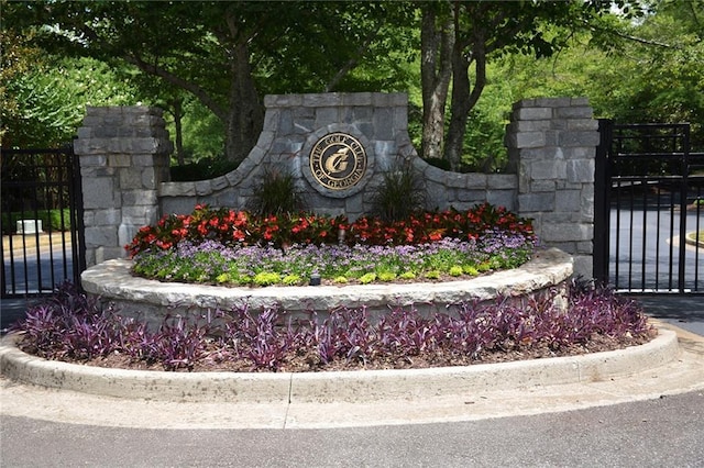 community / neighborhood sign with a gate and fence