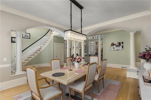 dining space with crown molding, visible vents, decorative columns, and wood finished floors