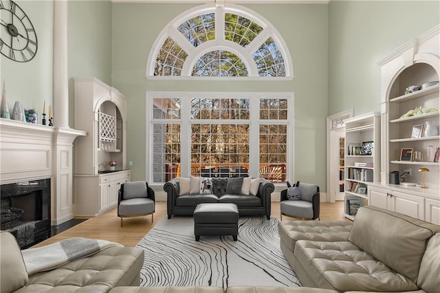 living area with a towering ceiling, light wood-style flooring, and a fireplace