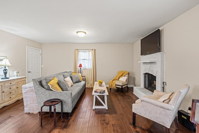 living room with a brick fireplace and dark wood-type flooring