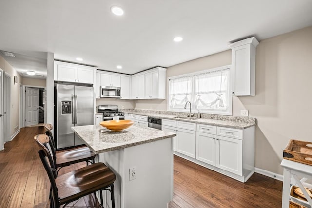 kitchen featuring stainless steel appliances, a center island, sink, and light stone counters