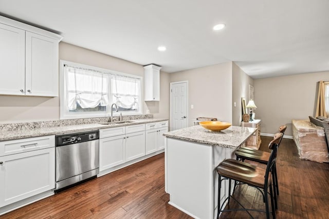 kitchen featuring sink, a breakfast bar, dishwasher, white cabinetry, and a center island