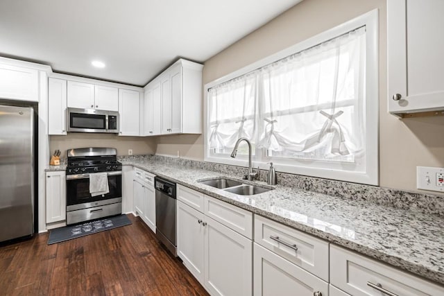 kitchen with dark wood-type flooring, sink, white cabinetry, appliances with stainless steel finishes, and light stone countertops