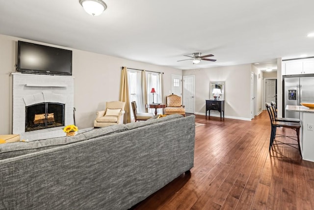 living room with dark hardwood / wood-style flooring, a fireplace, and ceiling fan