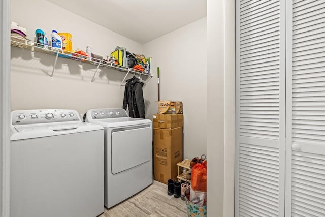 laundry room featuring separate washer and dryer and light hardwood / wood-style flooring