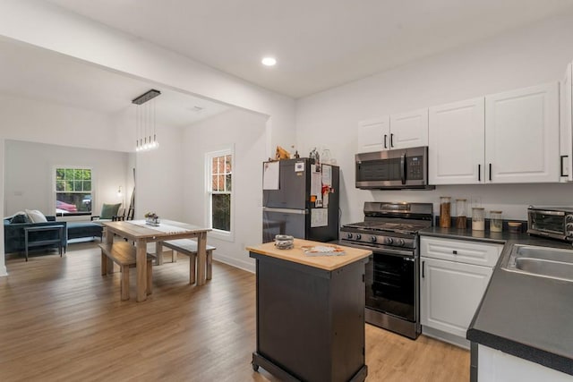 212 Haralson Ave NE, Atlanta, GA 30307 - kitchen with appliances with stainless steel finishes, white cabinets, light wood-style floors, decorative light fixtures, and recessed lighting